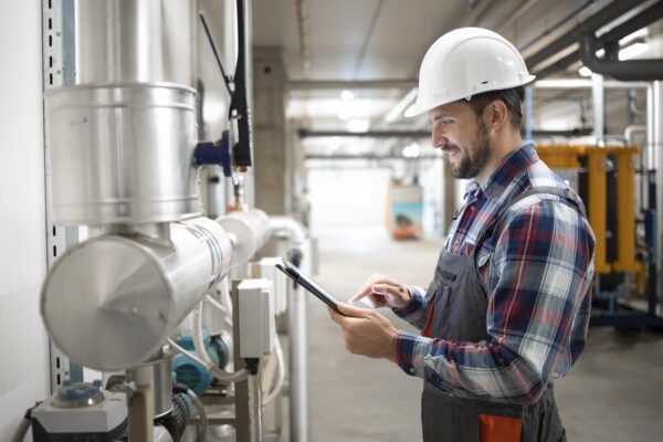 industrial-engineer-worker-holding-tablet-computer-and-setting-parameters-of-heating-system-in-factory-boiler-room-min